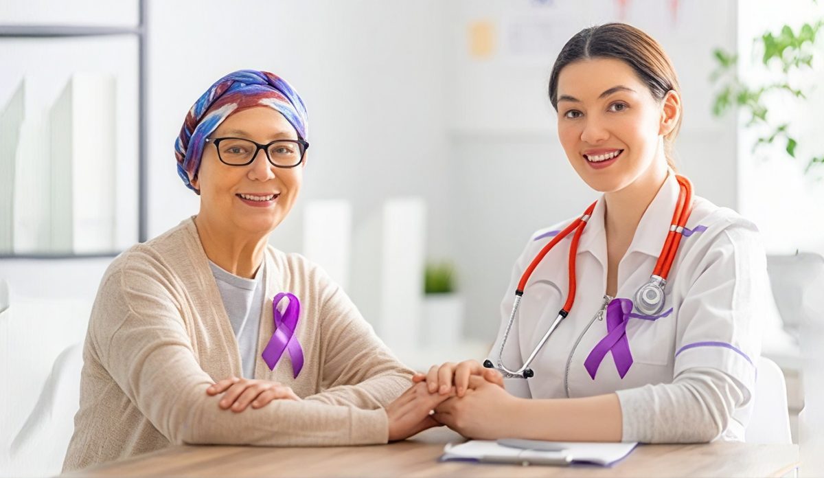 Smiling oncology patient wearing a headscarf seated beside a doctor, both wearing purple cancer-awareness ribbons